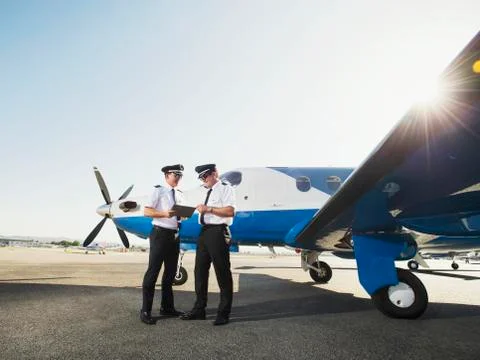 Caucasian pilots using digital tablet on runway Foto stock