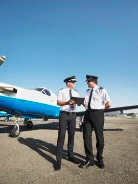 Caucasian pilots using digital tablet on runway Foto stock