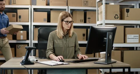 Caucasian post worker bringing box to woman who working at computer in delievery Stock Footage 125204675