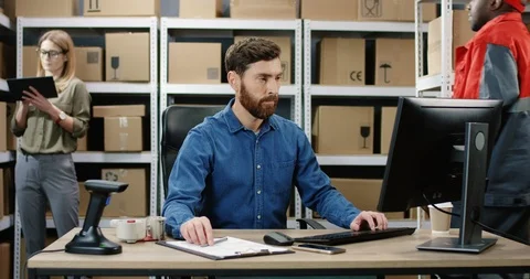 Caucasian postman working at computer in post delivery office and typing on Stock Footage 125217012