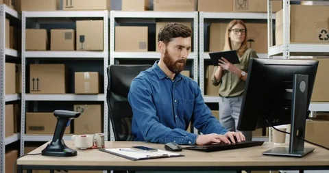 Caucasian postman working at computer in post delivery office and typing on Stock Footage 125218121