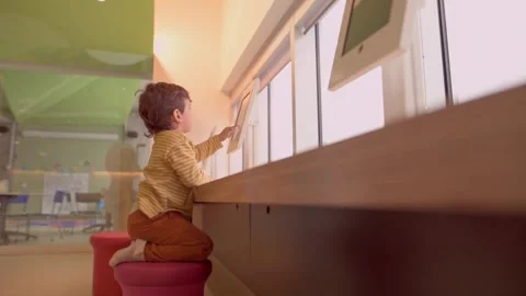 Caucasian pre school boy playing touch screen game on tablet indoor Stock Footage 246134339
