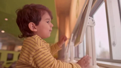 Caucasian pre school boy playing touch screen game on tablet indoor Stock Footage 258367422