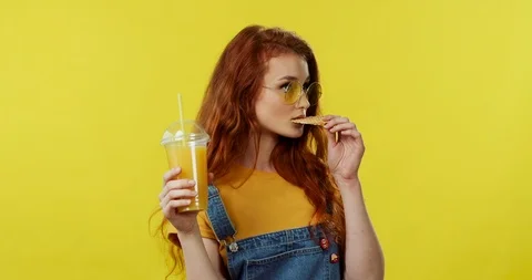 Caucasian pretty red-haired young woman in the sunglasses biting a cookie Stock Footage 105423985
