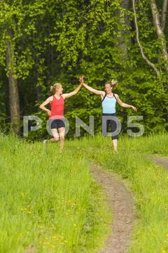 Caucasian runners high fiving on path Stock Photos