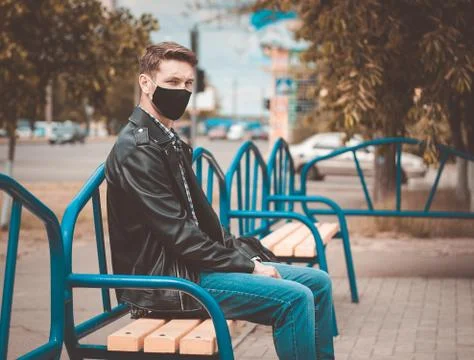 Caucasian sad men sits on the bench and turned his head to the left. He is lo Stock Photos