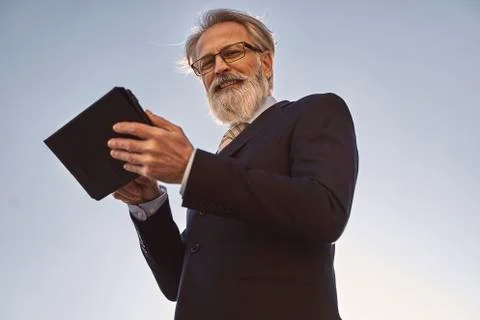 Caucasian senior CEO using a smart tablet  and looking in camera Stock Photos