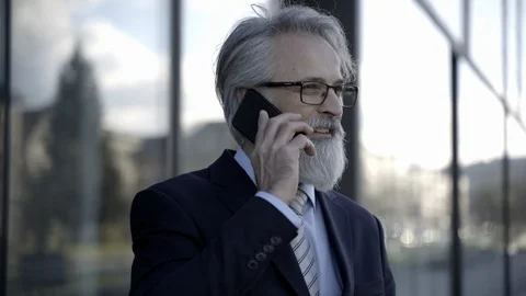 Caucasian senior CEO using a smartphone and smart tablet outside on a sunny day Stock Footage 109136702