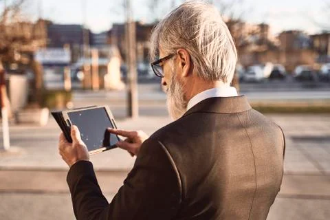 Caucasian senior CEO using a  tablet .outdoor shot. Stock Photos