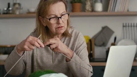 Caucasian senior woman is knitting with tutorial on the computer Video stock 167319246