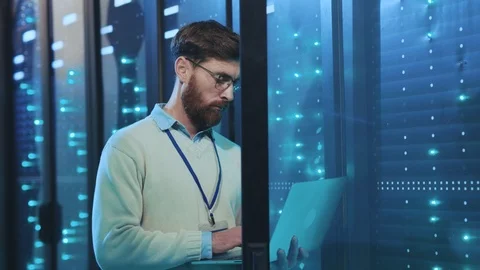 Caucasian server admin working on laptop with open server rack cabinet checking Stock Footage 119233228