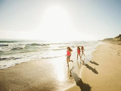 Caucasian sisters running on beach Stock Photos