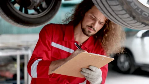 Caucasian Smart man checking car maintenance SUV suspension of a lifted car.. Stock Footage 242781139