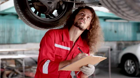 Caucasian Smart man checking car maintenance SUV suspension of a lifted car.. Stock Footage 242782184