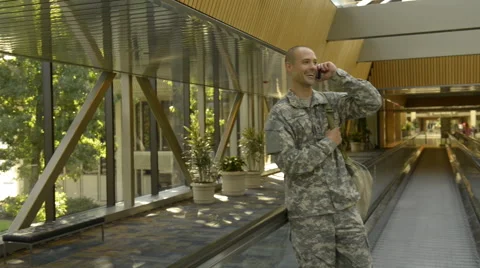 Caucasian soldier talking on cell phone in airport Stock Footage