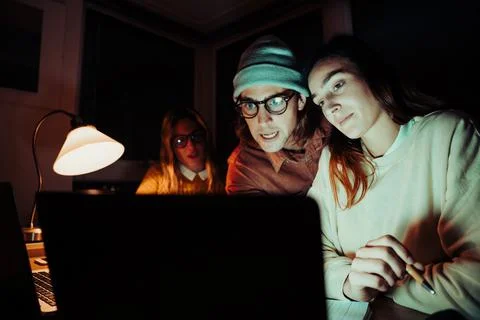 Caucasian students working late at night in home office typing on laptop Stock Photos