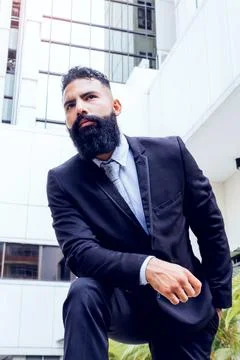 Caucasian successful adult businessman with long beard and suit looking at elega Stock Photos