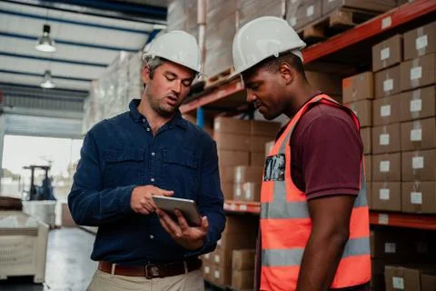 Caucasian supervisor explaining tips for improvement to ethnic worker in factory Stock Photos