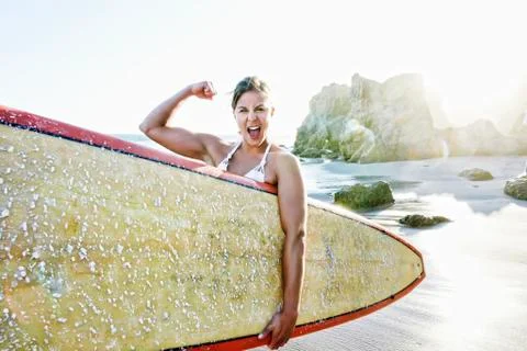 Caucasian surfer flexing muscle at beach Stock Photos