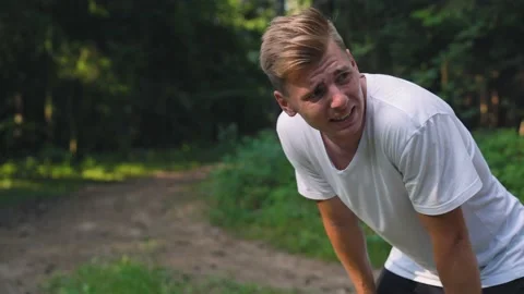 Caucasian sweating while catching breath after sprinting on the forest road. Stock Footage 157071346