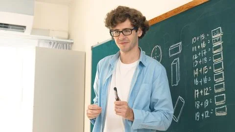 Caucasian teacher looking at student while standing at blackboard. Pedagogy. Stock Photos