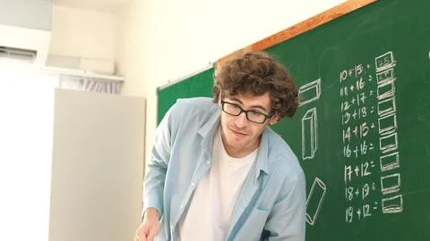 Caucasian teacher looking at student while standing at blackboard. Pedagogy. Stock Photos