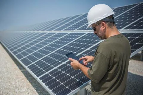 Caucasian technician using digital tablet near solar panels Fotos de archivo