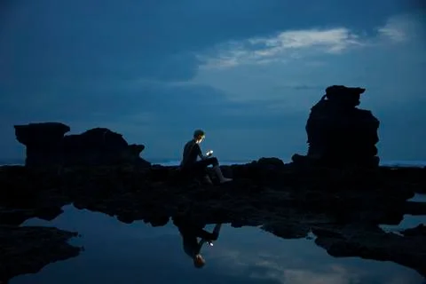 Caucasian teenage boy exploring rocky tidal pools at night, Canggu, Bali, Stock Photos