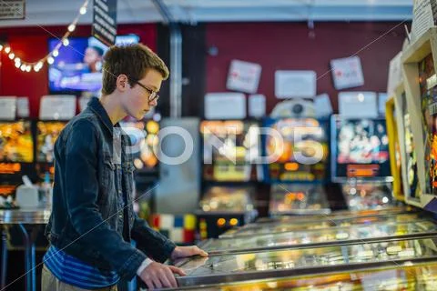 Caucasian teenage boy playing video game in arcade Stock Photos