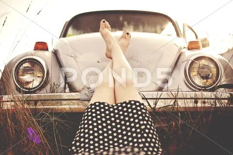Caucasian teenage girl resting feet on vintage car Stock Photos