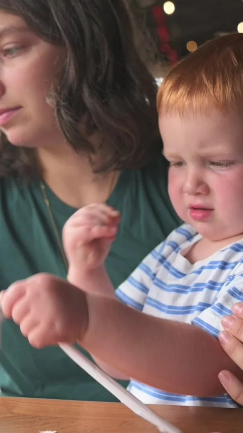 Caucasian toddler learning problem solving with straw, determined expression and Stock Footage 323095032