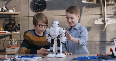 Caucasian two small happy friendly boys playing with a toy robot at the table in Stock Footage 135843400