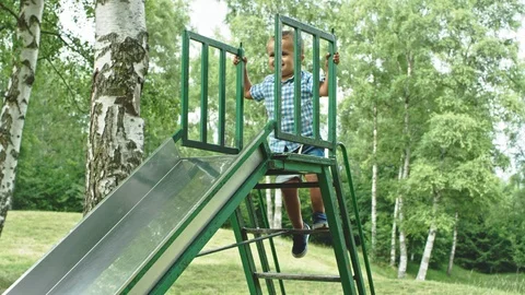 Caucasian two years old boy climbs the slide and claps his hands proudly 库存影片 98563339