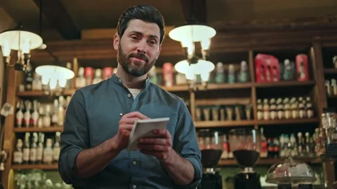 Caucasian waiter in uniform writing in notepad while taking guest order Stock Footage 260940439