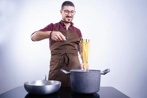 Caucasian white man with apron cooking homemade spaghetti on white background Stock Photos