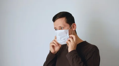 Caucasian white man puts a protective mask on his face and straightens it Stock Footage 129308927