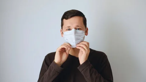 Caucasian white man puts on a protective mask on his face Stock Footage 129309051