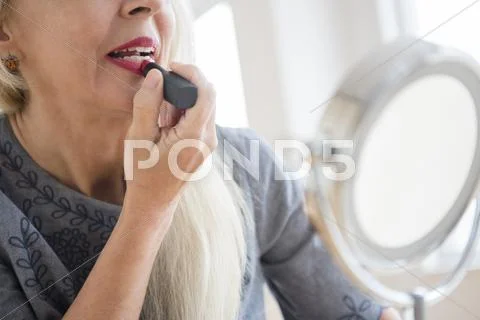 Caucasian Woman Applying Makeup In Mirror