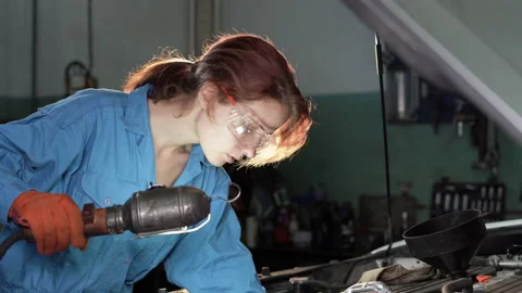 Caucasian woman auto mechanic doing a car inspection in her workshop. He holds a Stock Footage