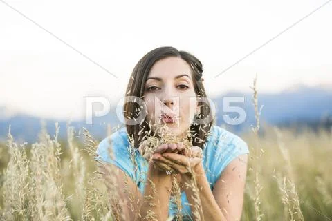 Caucasian Woman Blowing Seeds In Field