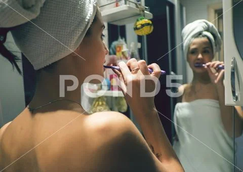 Caucasian woman brushing teeth in mirror Stock-Fotos