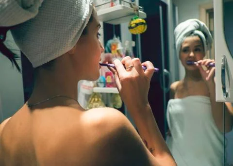 Caucasian woman brushing teeth in mirror Stock Photos