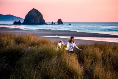 Caucasian woman carrying lantern on Cannon Beach, Oregon, United States Stock Photos