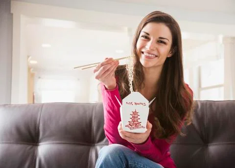Caucasian woman eating Chinese food on sofa Stock Photos