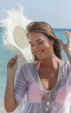 Caucasian woman holding sun hat at beach Stock Photos