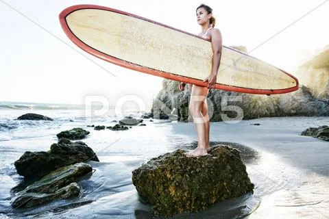 Caucasian woman holding surfboard at beach Stock Photos