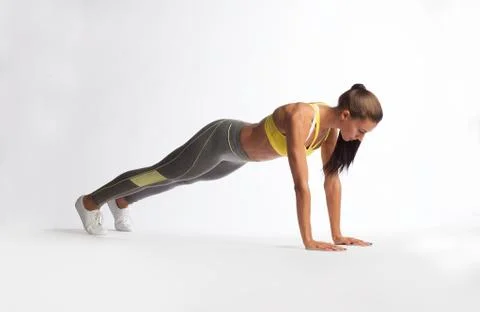 Caucasian woman in leggings doing push-ups on white background Stock Photos