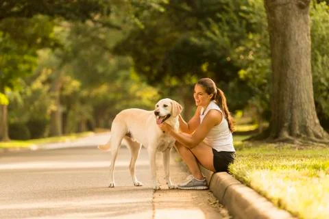 Caucasian woman petting dog on neighborhood street Stock Photos