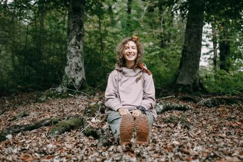 Caucasian woman sitting in autumn leaves in forest Stock Photos