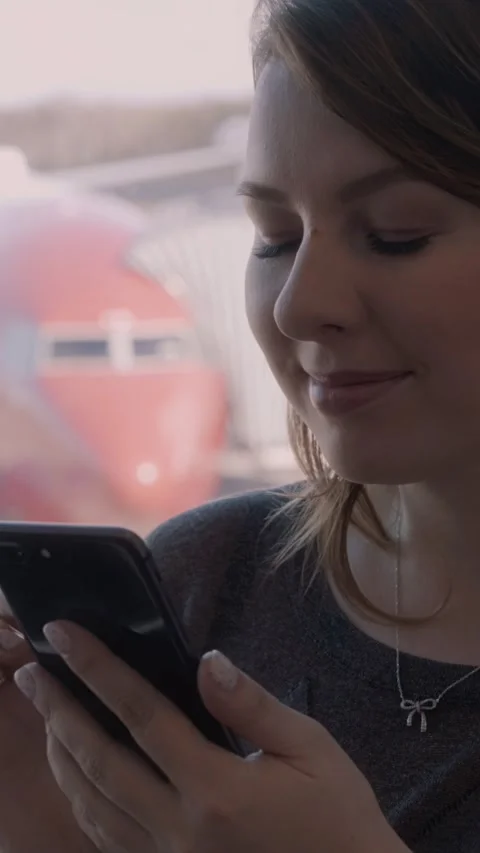 Caucasian woman smiling while using smartphone at airport terminal, airplane Vidéo 329201793